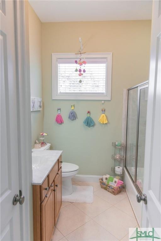 bathroom featuring tile patterned floors, toilet, enclosed tub / shower combo, baseboards, and vanity