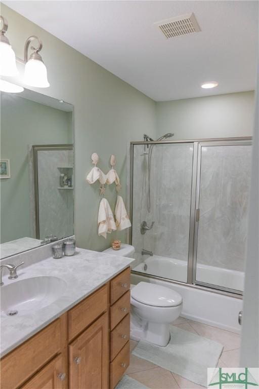 full bathroom featuring vanity, visible vents, bath / shower combo with glass door, tile patterned flooring, and toilet