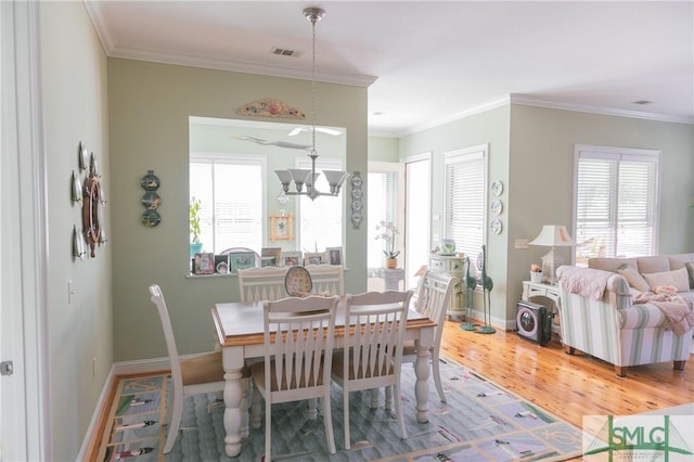 dining space featuring a wealth of natural light, visible vents, a notable chandelier, and wood finished floors