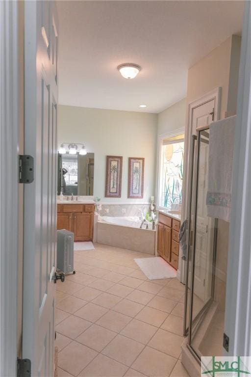 bathroom with a garden tub, a stall shower, vanity, and tile patterned flooring