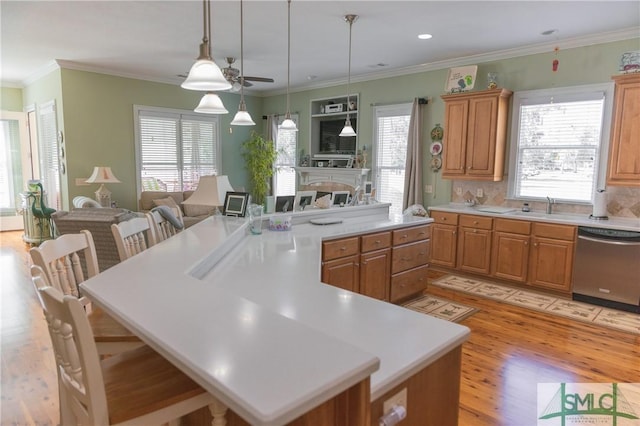 kitchen featuring a ceiling fan, plenty of natural light, light countertops, dishwasher, and a center island