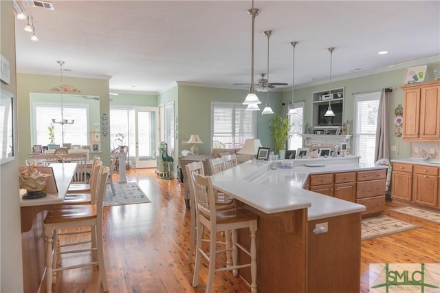 kitchen with light wood-type flooring, a breakfast bar area, and a ceiling fan