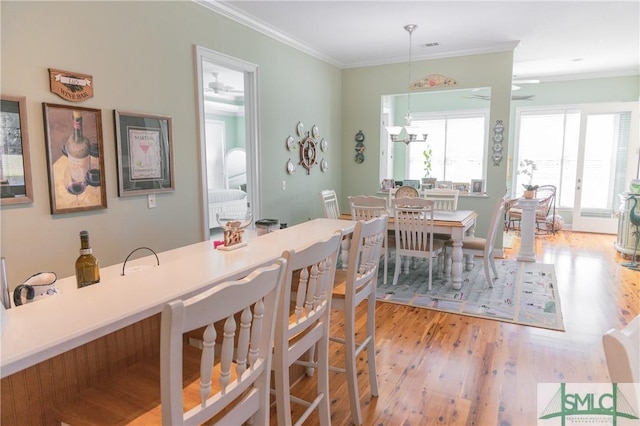 dining area with ceiling fan, light wood-style floors, and ornamental molding