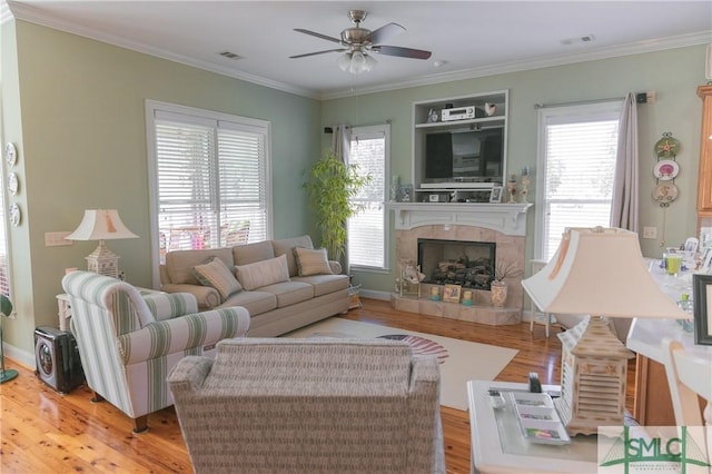 living room featuring visible vents, wood finished floors, a ceiling fan, and ornamental molding