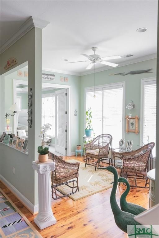 interior space with plenty of natural light, wood finished floors, and crown molding