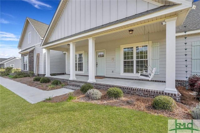 entrance to property featuring covered porch, board and batten siding, and a shingled roof