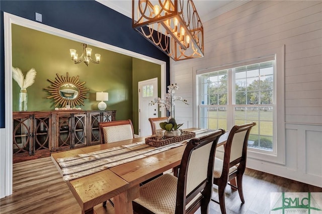 dining space with a notable chandelier, crown molding, and wood finished floors