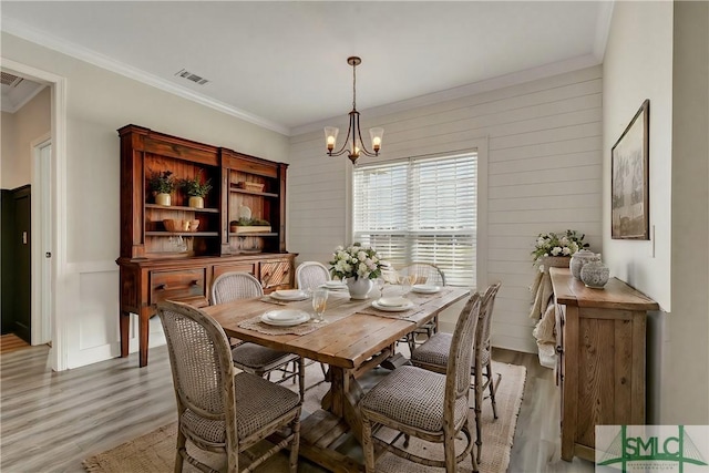 dining area featuring ornamental molding, visible vents, light wood finished floors, and a chandelier