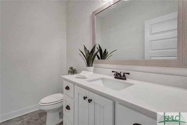 half bath with toilet, vanity, and baseboards