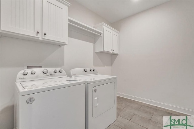 clothes washing area with separate washer and dryer, cabinet space, and baseboards