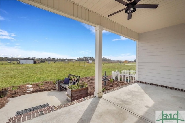 view of patio / terrace featuring a ceiling fan, a rural view, and fence