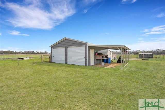 garage featuring a detached garage, a rural view, and fence