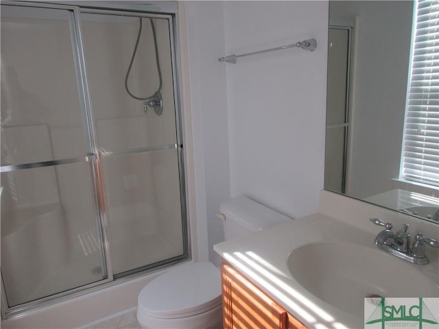 full bathroom with toilet, vanity, and a shower with shower door