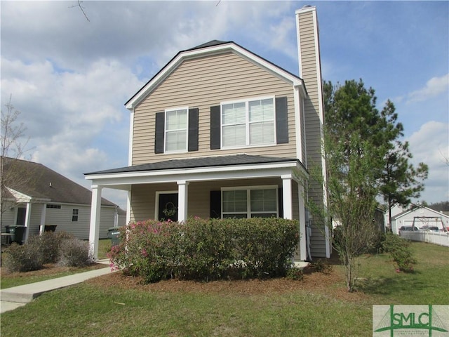 traditional-style home featuring covered porch, a chimney, and a front lawn