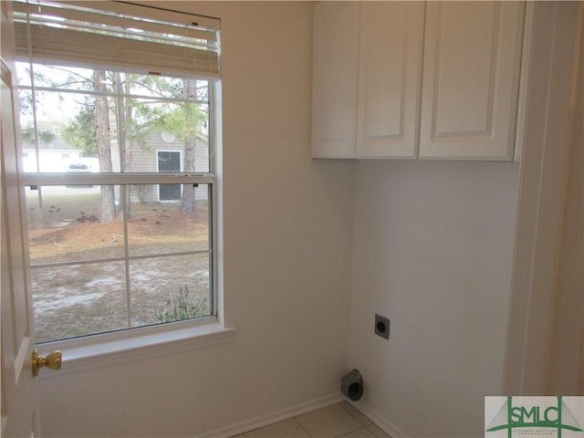 clothes washing area featuring tile patterned flooring, cabinet space, hookup for an electric dryer, and baseboards
