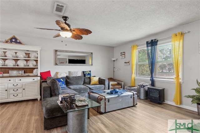 living room with a ceiling fan, baseboards, wood finished floors, visible vents, and a textured ceiling