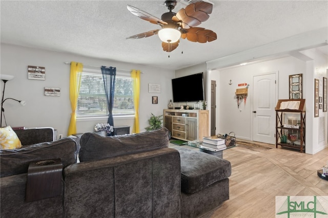 living room with light wood-style flooring, a textured ceiling, and a ceiling fan