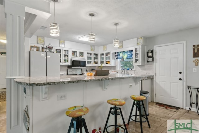 kitchen featuring a breakfast bar, white cabinets, glass insert cabinets, and backsplash