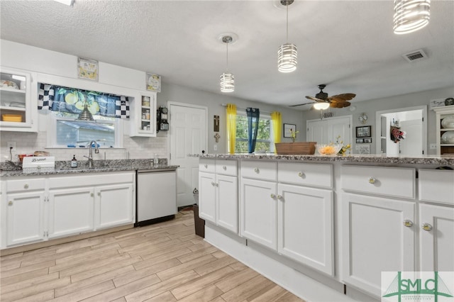 kitchen featuring a ceiling fan, light wood finished floors, a sink, decorative backsplash, and white cabinets