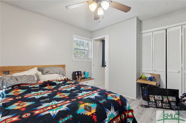 bedroom featuring a ceiling fan, a closet, light wood finished floors, and a textured ceiling