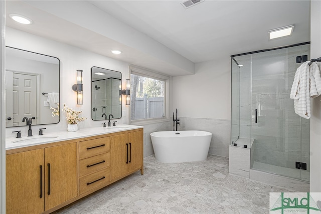 full bathroom with a sink, a freestanding tub, a stall shower, and double vanity