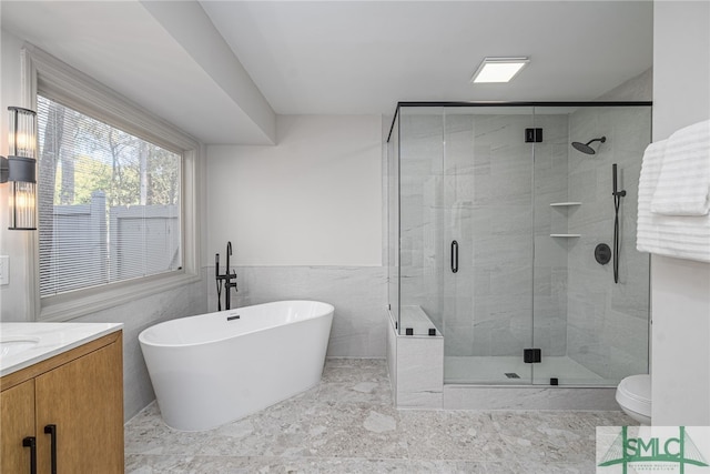 full bath featuring vanity, a freestanding bath, a shower stall, wainscoting, and toilet