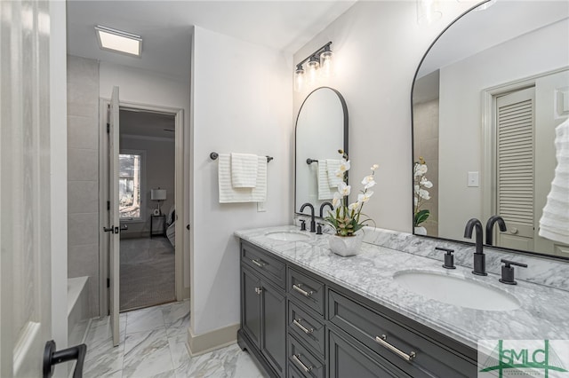 bathroom featuring double vanity, baseboards, marble finish floor, and a sink