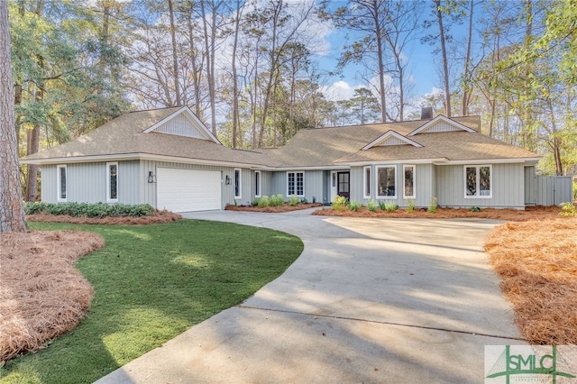 single story home with a chimney, an attached garage, concrete driveway, and a front lawn