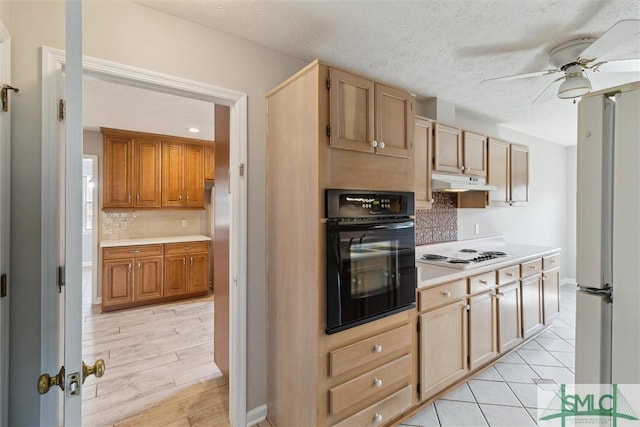 kitchen with oven, under cabinet range hood, white electric cooktop, light countertops, and a ceiling fan