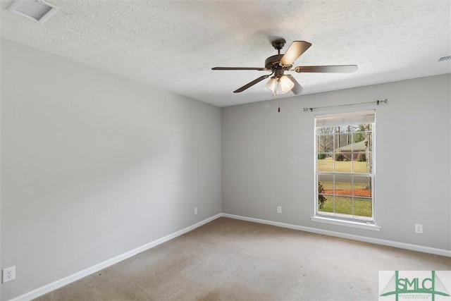 carpeted spare room with a textured ceiling, a ceiling fan, visible vents, and baseboards