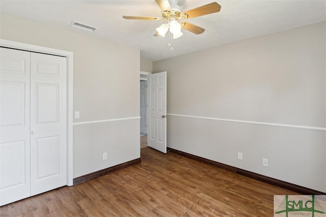 unfurnished bedroom with visible vents, baseboards, wood finished floors, a closet, and a ceiling fan