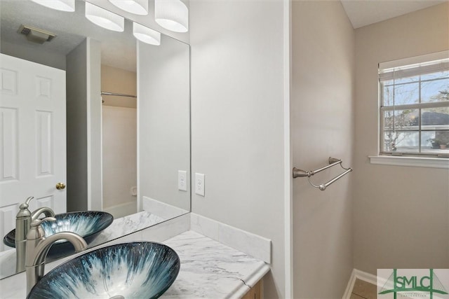 bathroom featuring vanity, baseboards, visible vents, and tile patterned flooring