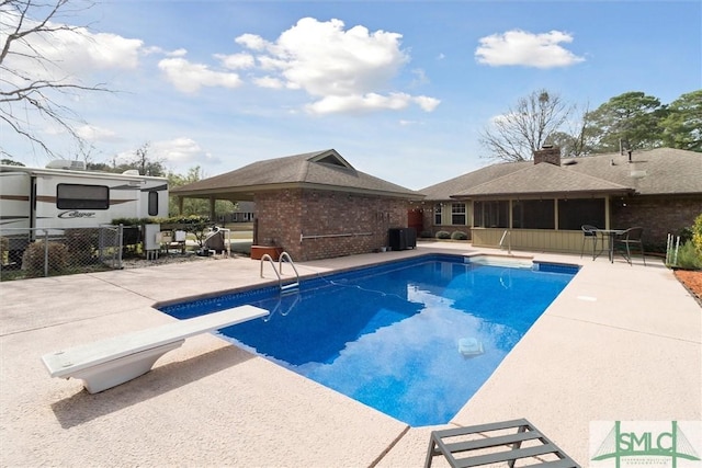 view of swimming pool featuring a diving board, a fenced in pool, fence, and a patio area