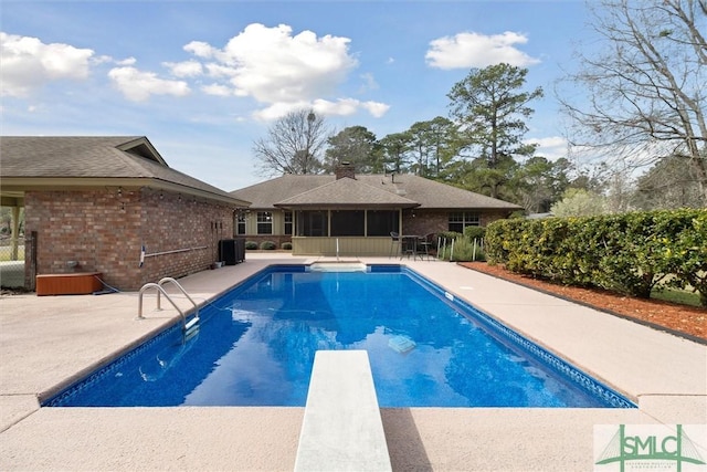 outdoor pool with a patio, central AC unit, a diving board, and a sunroom