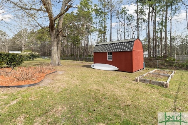 view of yard featuring a garden, a storage shed, an outbuilding, and fence