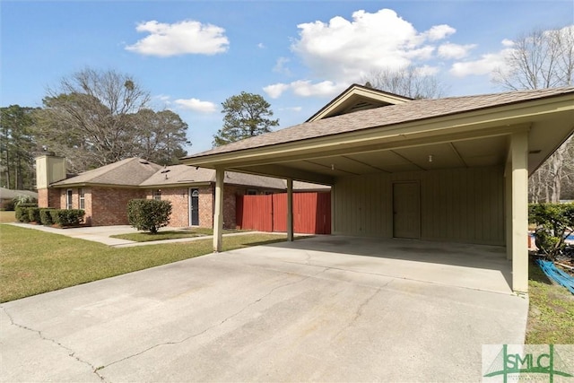 exterior space featuring a front yard, concrete driveway, fence, and a chimney