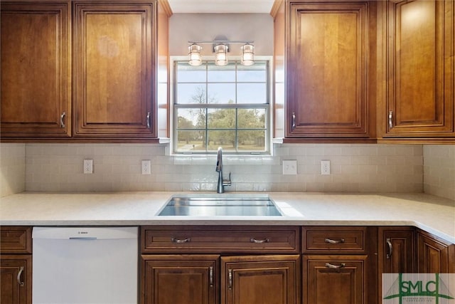 kitchen featuring tasteful backsplash, dishwasher, light countertops, and a sink