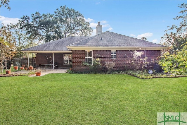 rear view of house featuring brick siding, a lawn, and a patio