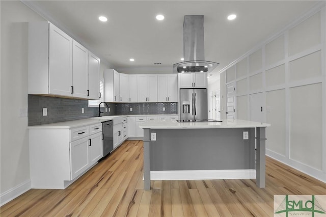 kitchen featuring a decorative wall, stainless steel fridge, dishwasher, and island exhaust hood