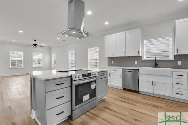 kitchen with a sink, appliances with stainless steel finishes, light countertops, and island range hood