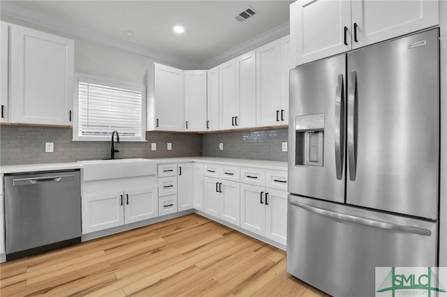 kitchen featuring light countertops, stainless steel appliances, light wood-style floors, white cabinetry, and a sink