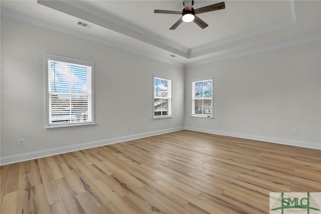 spare room with light wood finished floors, visible vents, baseboards, ceiling fan, and a raised ceiling