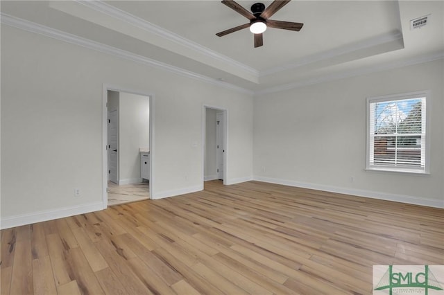unfurnished bedroom with visible vents, baseboards, a tray ceiling, ornamental molding, and light wood-type flooring