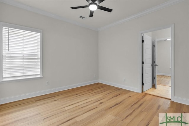 spare room featuring a ceiling fan, visible vents, baseboards, light wood-style flooring, and crown molding