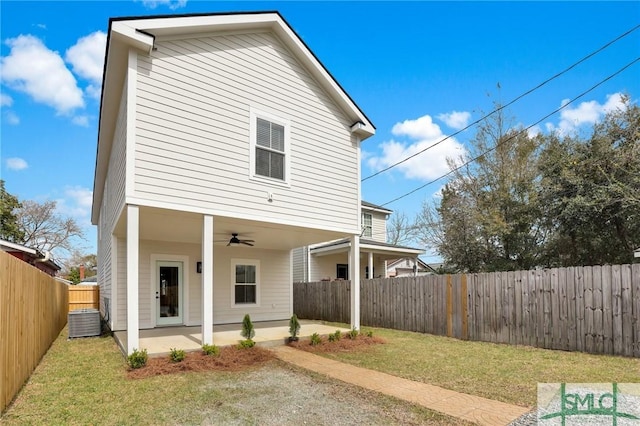 back of house featuring a fenced backyard, ceiling fan, central air condition unit, a patio area, and a lawn