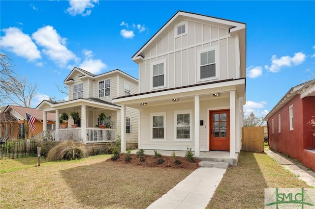 view of front facade with covered porch, board and batten siding, a front yard, and fence