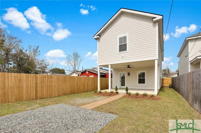 rear view of house featuring a fenced backyard, a lawn, and ceiling fan