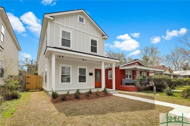 view of front facade featuring board and batten siding, a front lawn, fence, a porch, and a gate