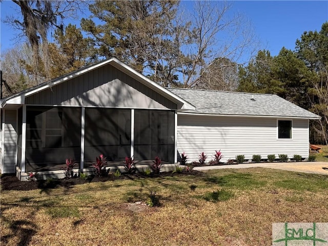 view of home's exterior with roof with shingles, a yard, and a sunroom