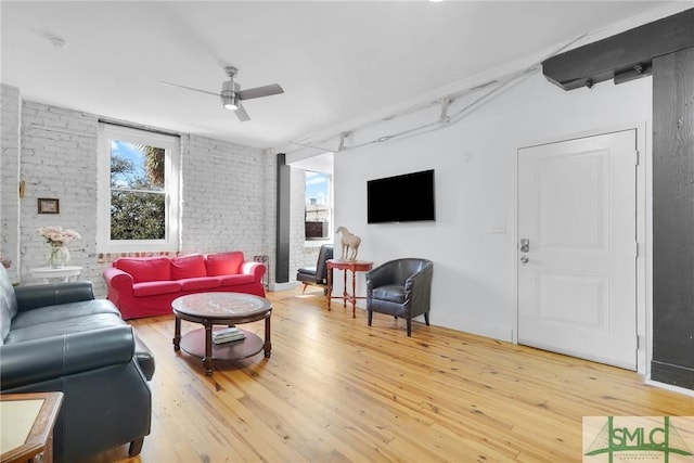 living area with light wood-style flooring, brick wall, and ceiling fan